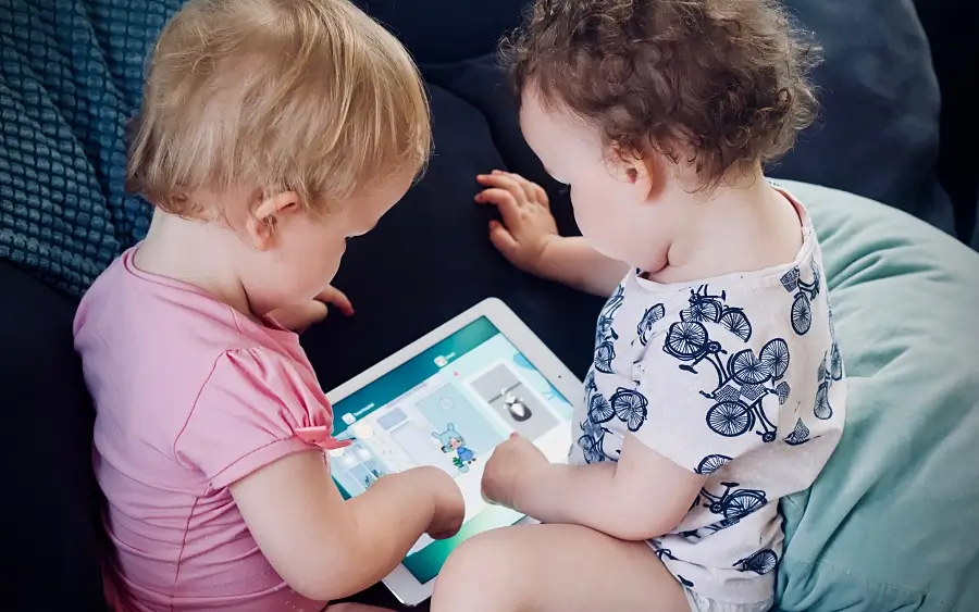Zwei Kleinkinder sitzen alleine vor dem Tablet und spielen